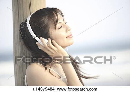 Japanese woman listening to music on a beach View Large Photo Image Picture - Japanese woman listening to music on a beach. Fotosearch