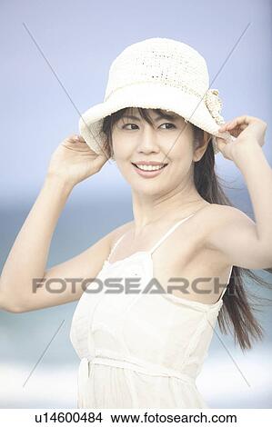 Japanese woman putting on a hat View Large Photo Image Picture - Japanese woman putting on a hat. Fotosearch