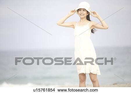 Japanese woman putting on a hat View Large Photo Image Picture - Japanese woman putting on a hat. Fotosearch