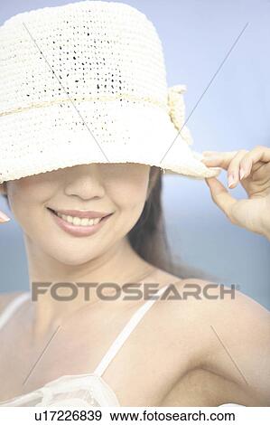 Stock Photo - Japanese woman putting on a hat. Fotosearch