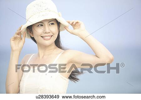 Stock Photo - Japanese woman putting on a hat. Fotosearch
