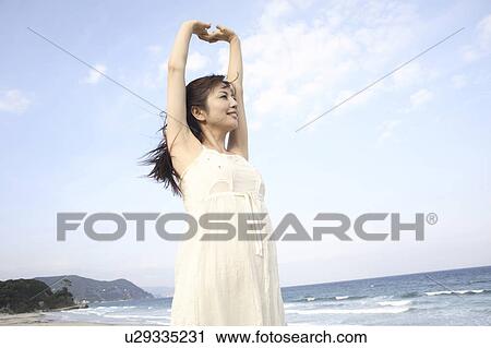 Stock Image - Japanese woman stretching on a beach. Fotosearch
