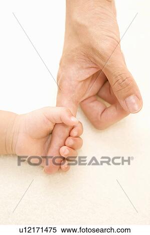 Stock Photography - Baby touching his father's finger. Fotosearch