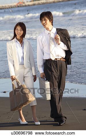 Stock Photo - Japanese couple walking along a beach. Fotosearch