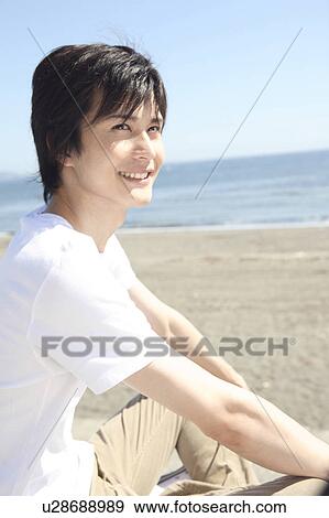 Stock Photo - Japanese man sitting on the beach. Fotosearch