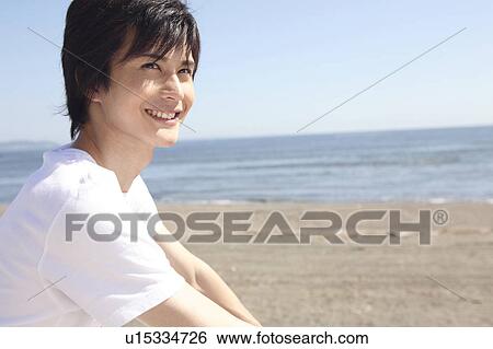 Stock Photograph - Japanese man sitting on the beach. Fotosearch
