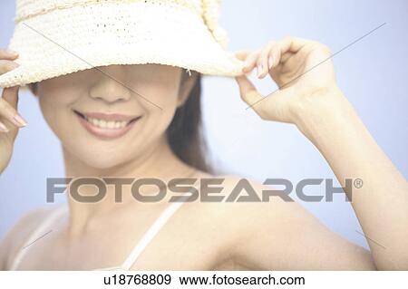 Stock Photo - Japanese woman putting on a hat. Fotosearch