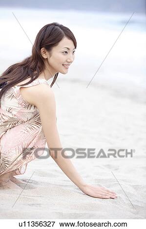 Stock Photo - Japanese woman sitting on a beach. Fotosearch