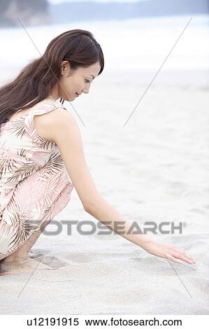 Stock Photography - Japanese woman sitting on a beach. Fotosearch