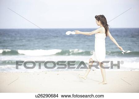 Picture - Japanese woman walking along a beach. Fotosearch