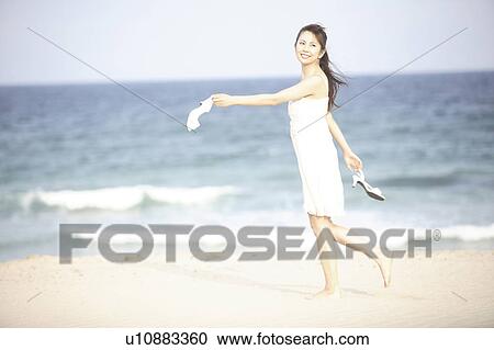Stock Image - Japanese woman walking along a beach. Fotosearch