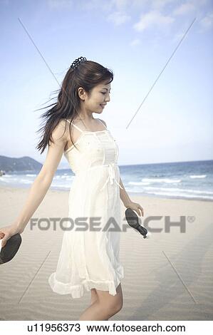 Stock Image - Japanese woman walking along a beach. Fotosearch