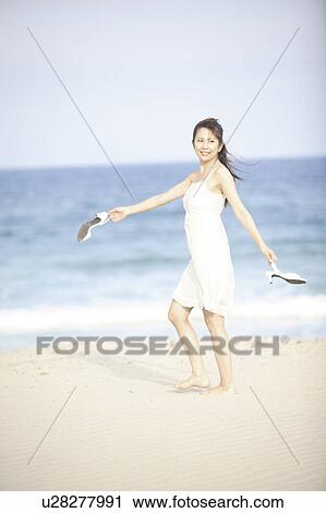Stock Image - Japanese woman walking along a beach. Fotosearch