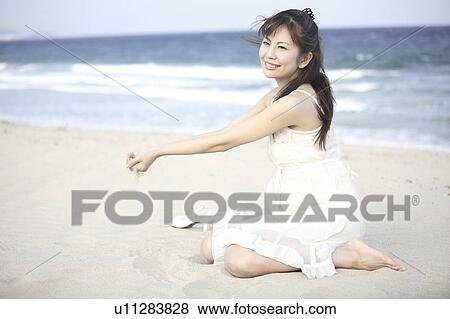 Stock Photo - Woman scooping the sand of the sandy beach. Fotosearch