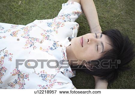 Stock Photo - Japanese man lying down on the grass. Fotosearch