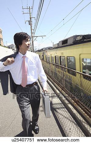 Japanese office worker walking along railroad View Large Photo Image Stock Image - Japanese office worker walking along railroad. Fotosearch