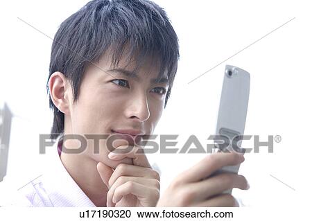 Stock Image - Man checking e-mail by cell phone. Fotosearch