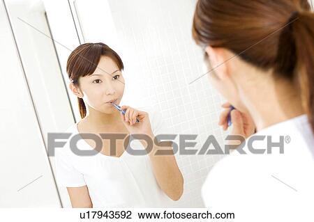 Stock Image - Japanese woman brushing teeth. Fotosearch