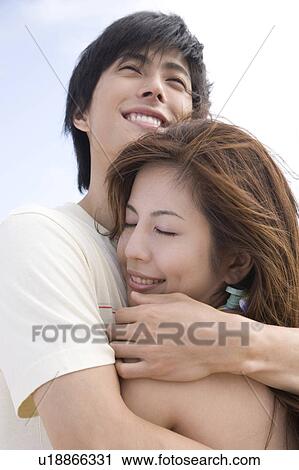 Stock Image - Couple hugging each other on a beach. Fotosearch