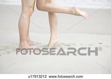 Stock Image - Foot of couple on a beach. Fotosearch