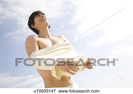 Stock Photo - Japanese man taking off a shirt. Fotosearch