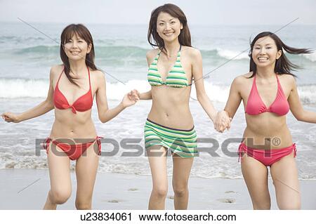 Stock Image - Japanese weman running on a beach in swimsuit. Fotosearch