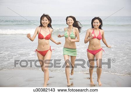 Stock Image - Japanese weman running on a beach in swimsuit. Fotosearch