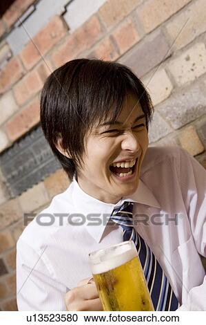 Stock Image - Office worker drinking a beer with joy. Fotosearch