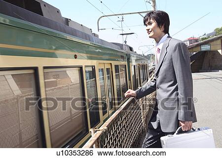 Stock Photograph - Office worker looking at passing train. Fotosearch