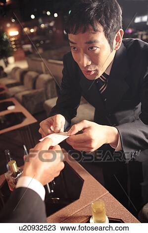 Stock Image - Japanese office worker handing a business card. Fotosearch