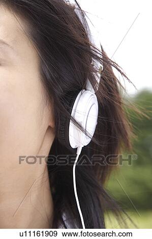 Stock Photo - Japanese woman listening to the music in a park. Fotosearch