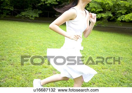 Stock Image - Japanese woman running in the park. Fotosearch