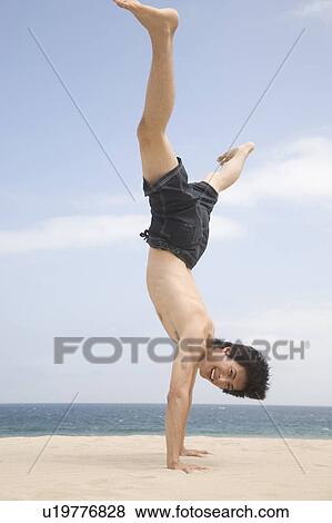 Stock Photo - Japanese man doing gymnastics on a beach. Fotosearch
