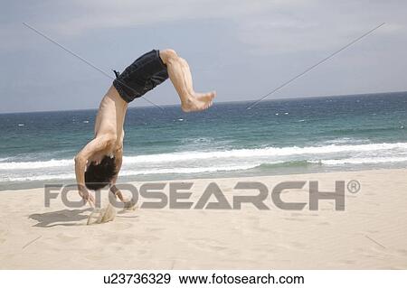 Stock Photo - Japanese man doing gymnastics on a beach. Fotosearch