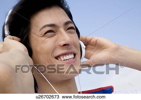 Stock Image - Japanese man listening to music. Fotosearch