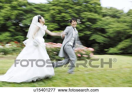 Stock Photo - Bridal couple running in garden. Fotosearch