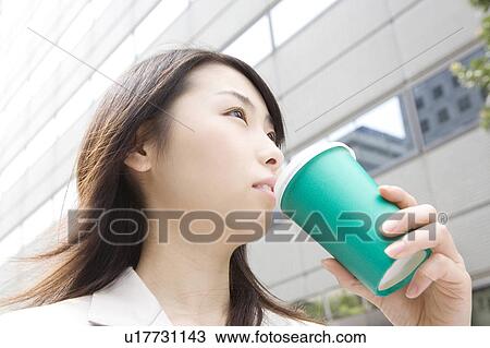 Stock Image - Business woman walking and drinking a coffee. Fotosearch