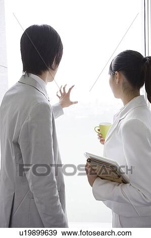 Stock Photo - Coworkers looking out office window. Fotosearch