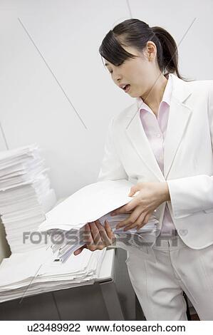 Stock Image - Office lady putting documents in order. Fotosearch