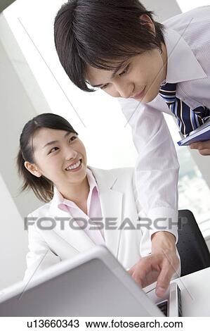 Stock Image - Office worker looking at monitor with smile. Fotosearch