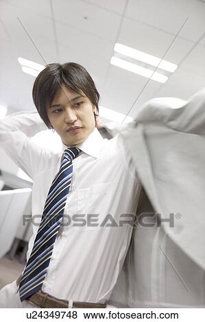 Stock Photo - Office worker putting on suitcoat. Fotosearch