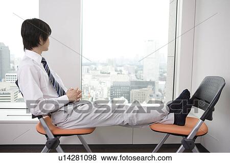 Office worker taking a break with stretching his foot on a chair View Large Photo Image Stock Photo - Office worker taking a break with stretching his foot on a chair. Fotosearch