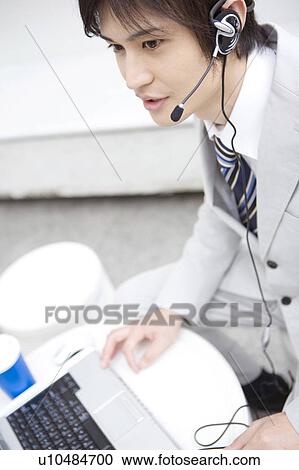 Stock Image - Office worker talking with headset. Fotosearch