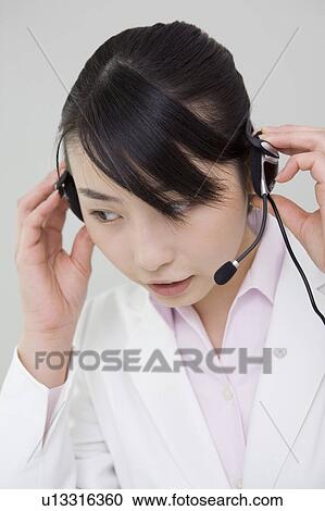Woman putting on a headset View Large Photo Image Stock Image - Woman putting on a headset. Fotosearch