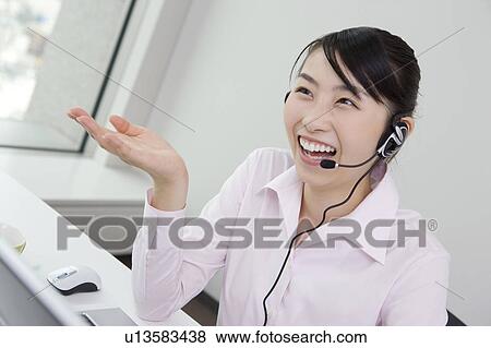 Young business woman putting on a headset View Large Photo Image Stock Photo - Young business woman putting on a headset. Fotosearch