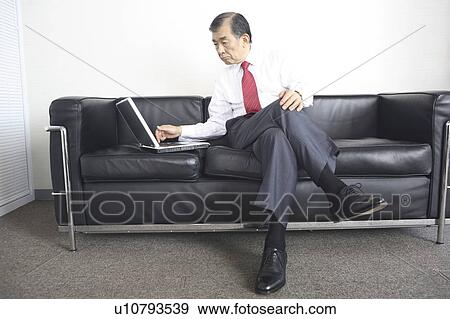 Stock Photo - Businessman on a sofa with a laptop. Fotosearch