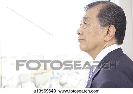 Stock Image - Chief executive officer looking at outside from room. Fotosearch