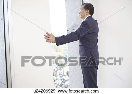 Stock Photo - Chief executive officer looking at outside from room. Fotosearch