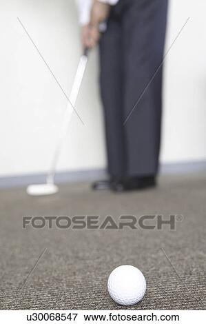 Stock Photo - Japanese chief executive officer practicing golf. Fotosearch