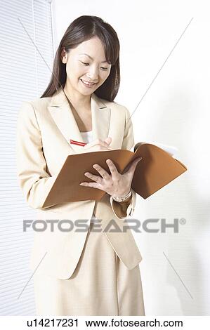 Stock Image - Japanese office lady taking a memo. Fotosearch
